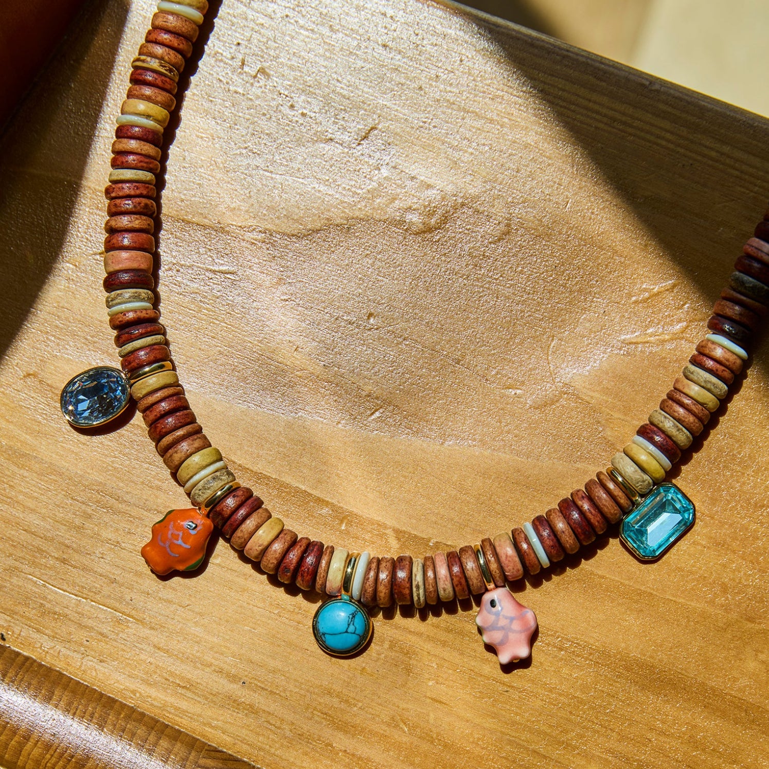Necklace with multicolored beads and charms on a wooden surface