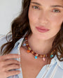 Woman wearing a colorful beaded necklace with a neutral background