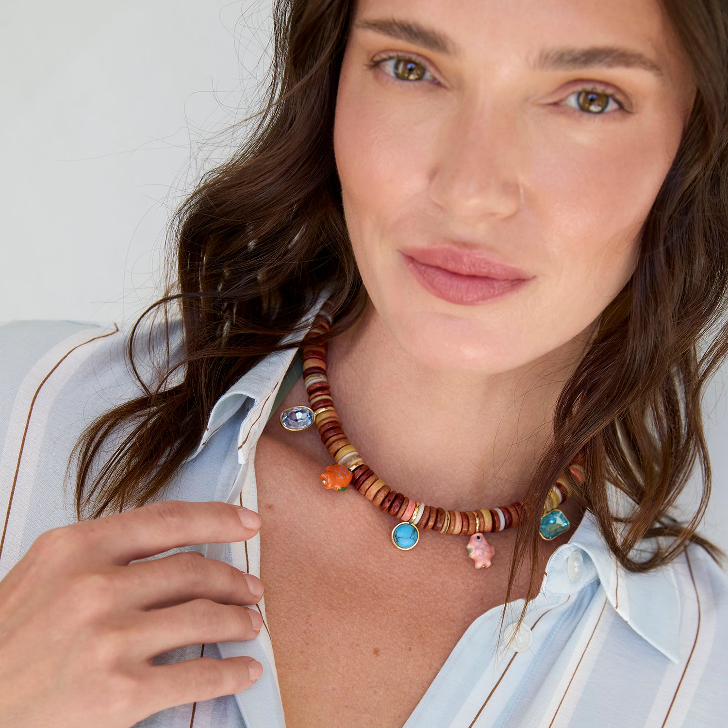 Woman wearing a colorful beaded necklace with a neutral background