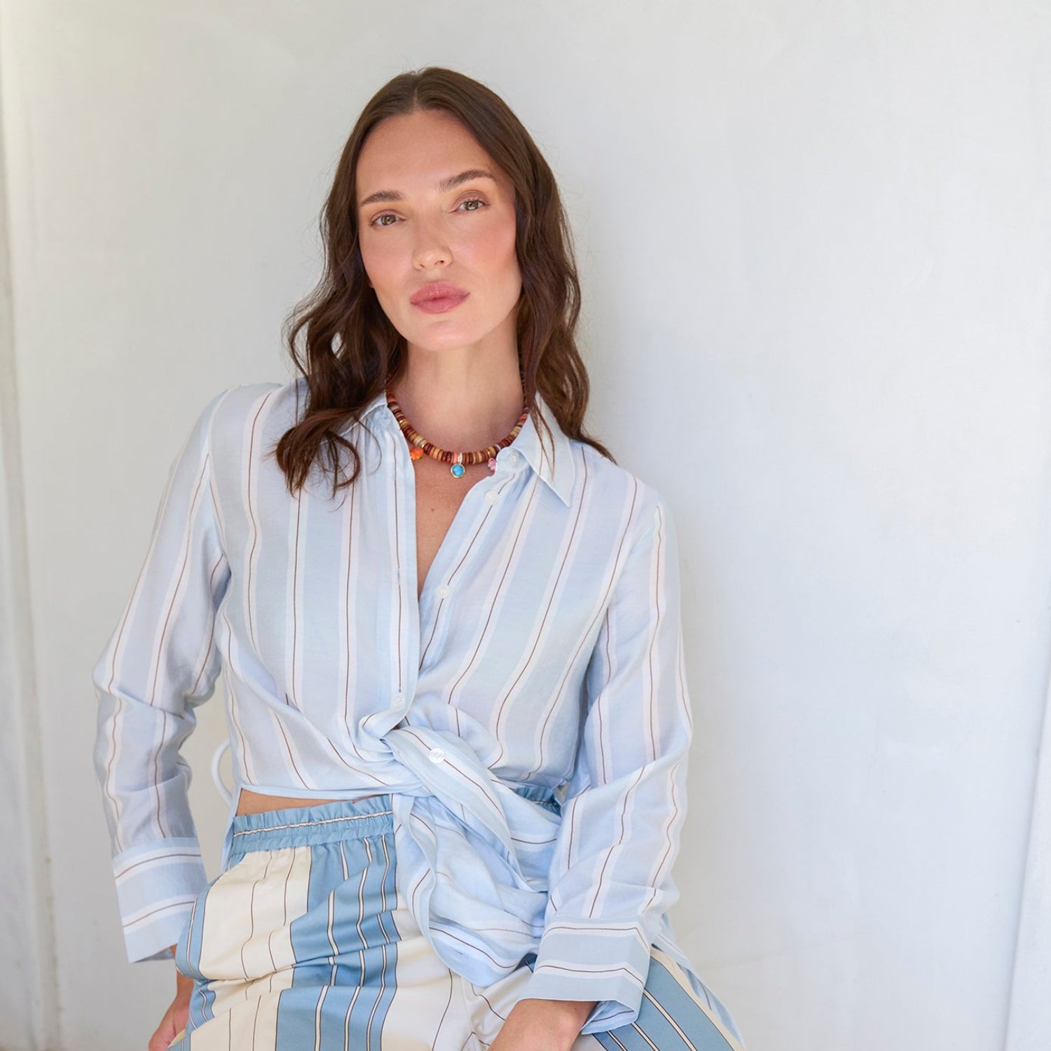 Woman wearing a light blue and white striped outfit against a white background