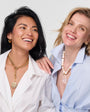 Two women wearing necklaces against a white background