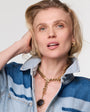 Woman wearing a denim jacket and gold necklace on a white background