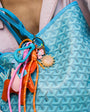 Close-up of a patterned bag with colorful keychains and a visible brand logo.