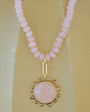 Necklace with pink beads and a gold pendant on a beige background