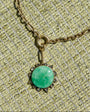 Necklace with a green pendant on a textured beige background