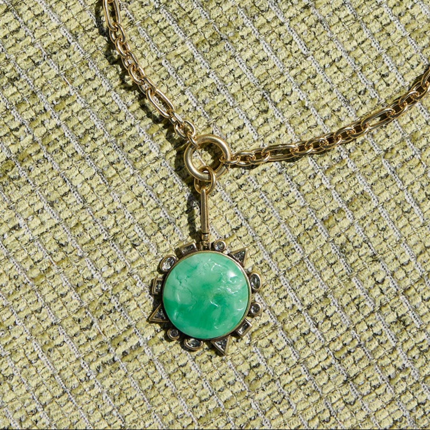 Necklace with a green pendant on a textured beige background