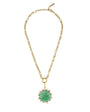 A gold chain necklace featuring a round green cabochon gemstone pendant surrounded by a halo of small clear stones, displayed on a solid white background.