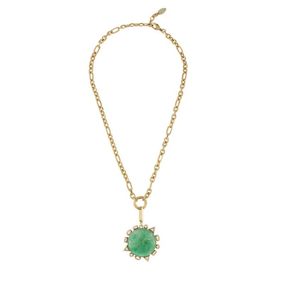 A gold chain necklace featuring a round green cabochon gemstone pendant surrounded by a halo of small clear stones, displayed on a solid white background.