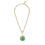 A gold chain necklace featuring a round green cabochon gemstone pendant surrounded by a halo of small clear stones, displayed on a solid white background.