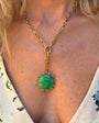 Close-up of a necklace with a green pendant worn by a person.