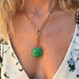 Close-up of a necklace with a green pendant worn by a person.