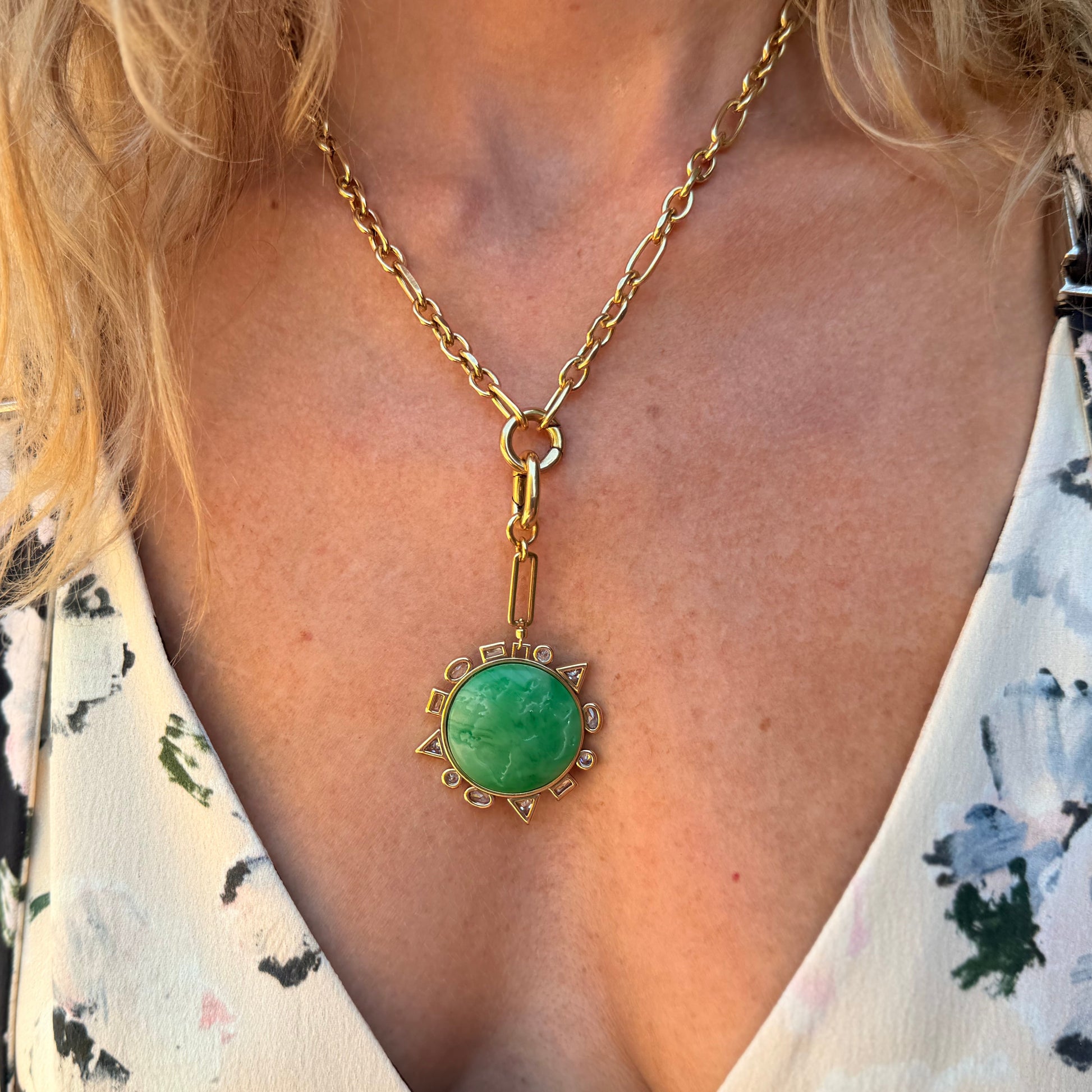 Close-up of a necklace with a green pendant worn by a person.