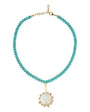 A beaded necklace featuring small turquoise-blue beads on a gold-tone chain, with a central oval white mother-of-pearl pendant surrounded by small clear stones and gold-tone accents.