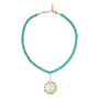 A beaded necklace featuring small turquoise-blue beads on a gold-tone chain, with a central oval white mother-of-pearl pendant surrounded by small clear stones and gold-tone accents.