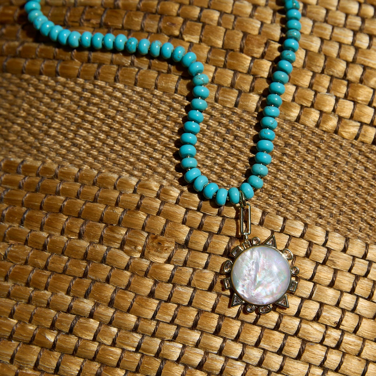 Turquoise beaded necklace with a pendant on a woven surface