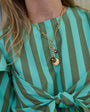 Model wearing  charm and chain necklace with a striped shirt