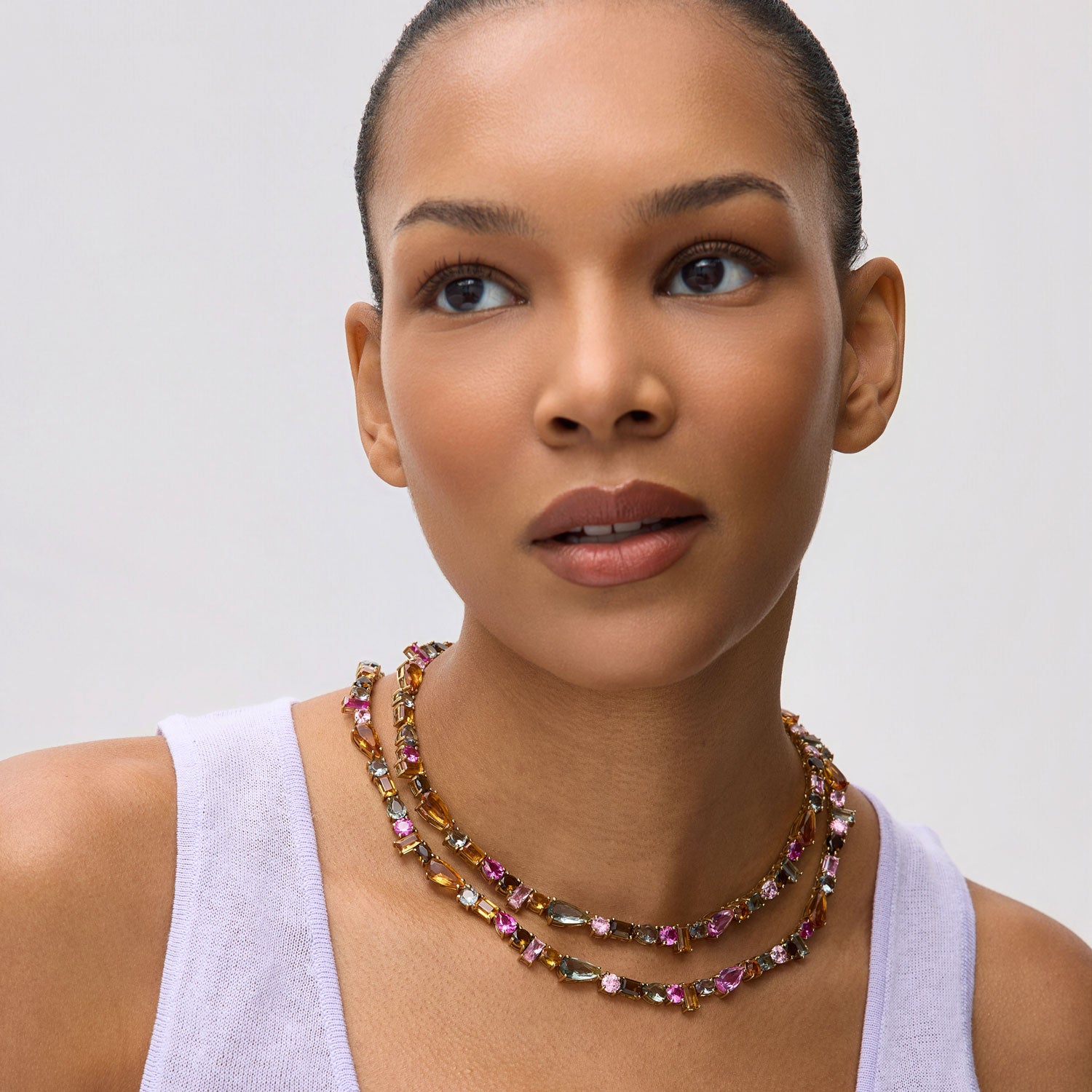 Woman wearing a colorful beaded necklace against a plain background