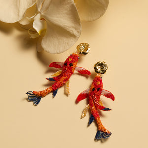 Orange Beaded and Embroidered Koi Fish Drop Earrings Staged on Cream Surface with Orchid