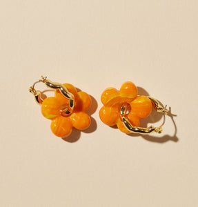 Orange and Yellow Marbled Glass Flower Charm Earrings on Gold Hoop on Flat Cream Background