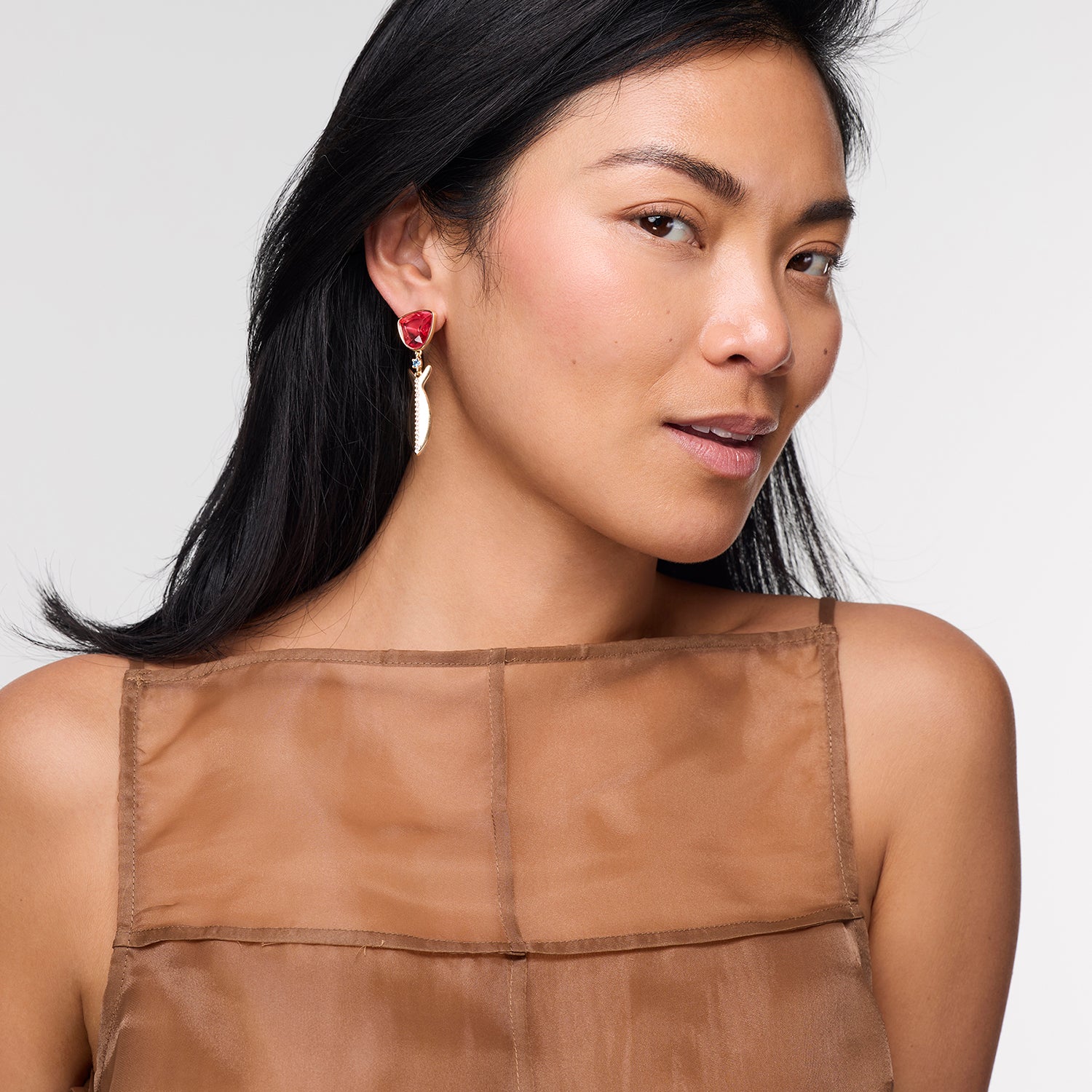 Model wearing Paula Earrings with red gemstone on white background