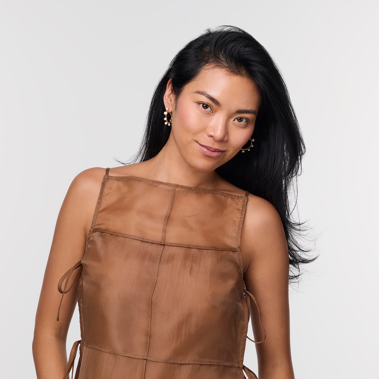 Woman wearing a brown sleeveless top against a white background