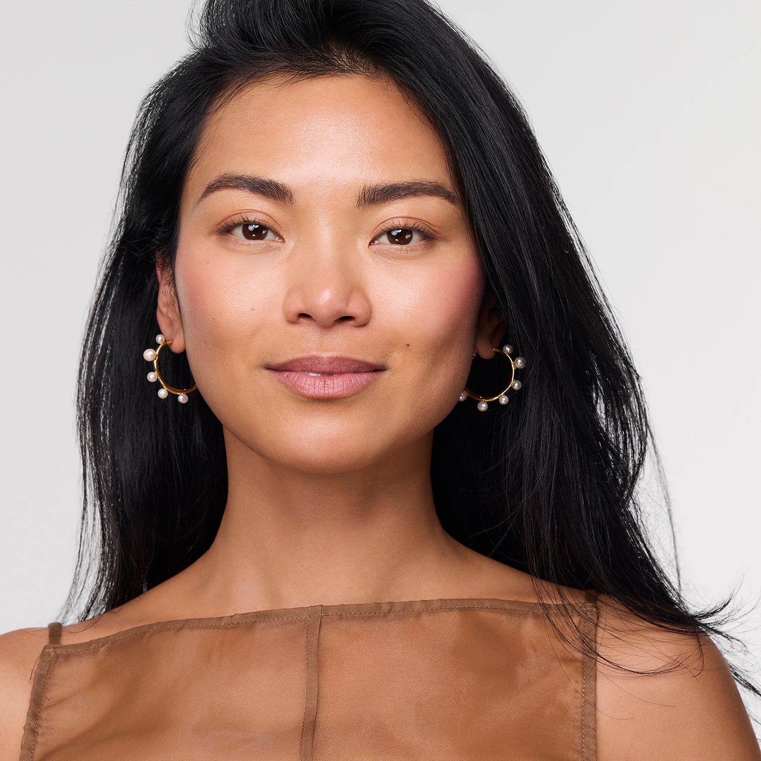 Model wearing pearl and gold hoop earring