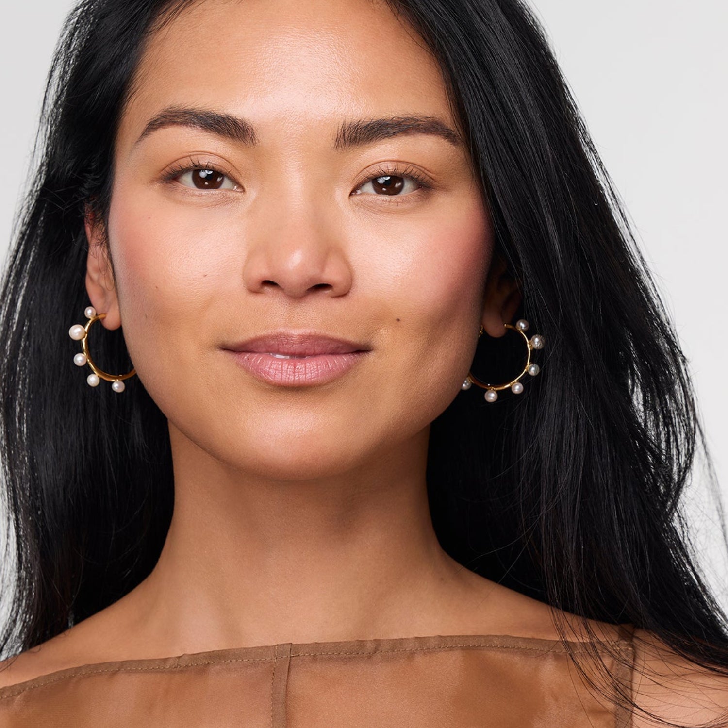 Model wearing pearl and gold hoop earring
