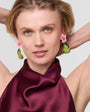 Woman wearing pink and green Pera Earrings with a plain background