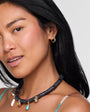 Woman wearing a necklace and earrings against a neutral background