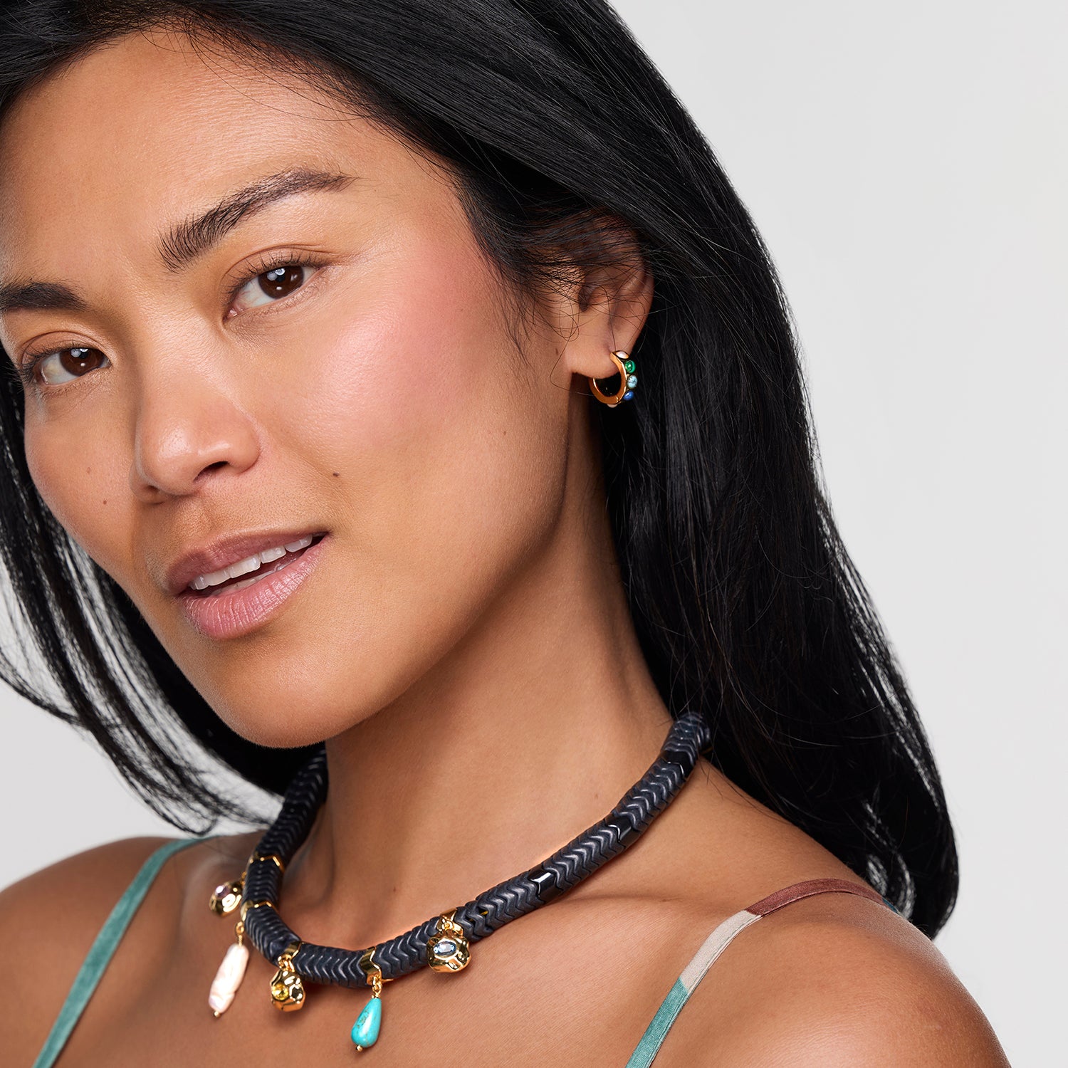 Woman wearing a necklace and earrings against a neutral background