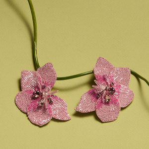 Pink Beaded and Crystal Flower Stud Earrings Staged with Flower Stem on Green Background
