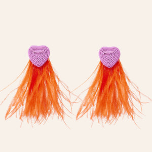 Pink Beaded Heart Earrings with Red Statement Feathers on Cream Background