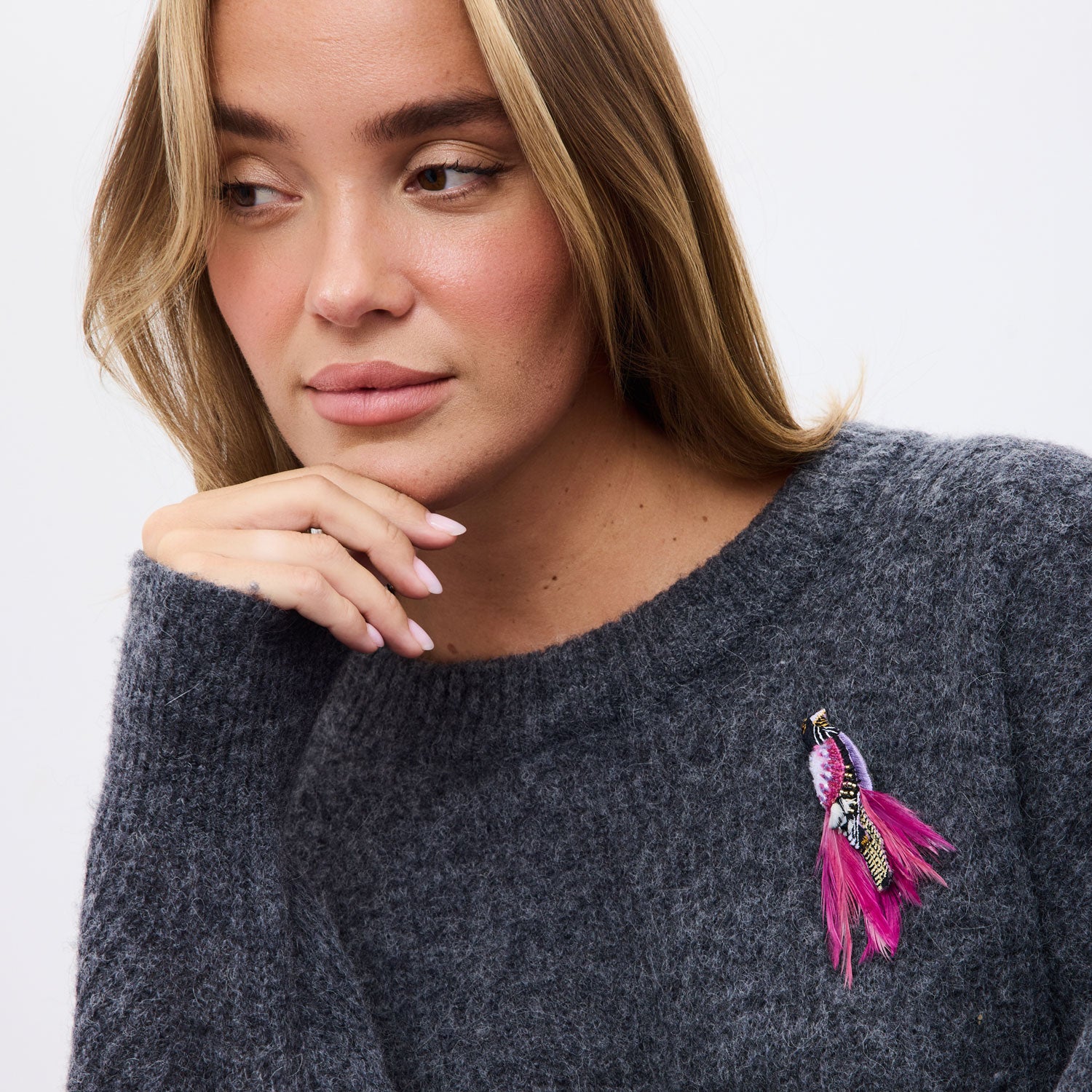 model wearing grey sweater with feather bird brooch