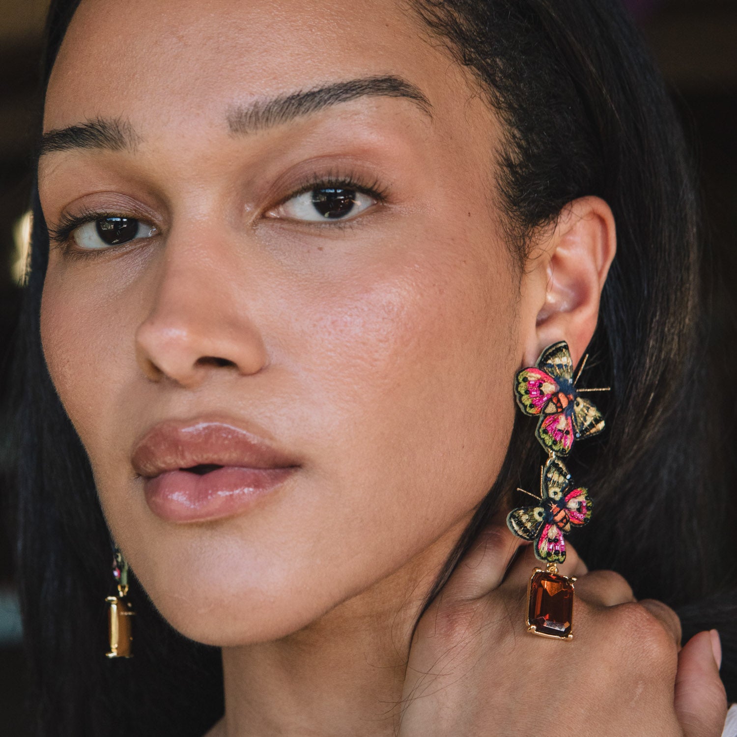Close-up of a woman wearing colorful earrings with a blurred background