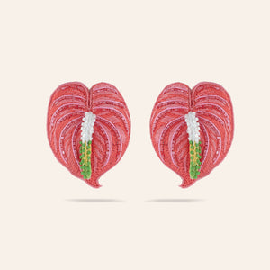 Pink, White, and Green Beaded and Embroidered Anthurium Flower Stud Earrings on Tan Background