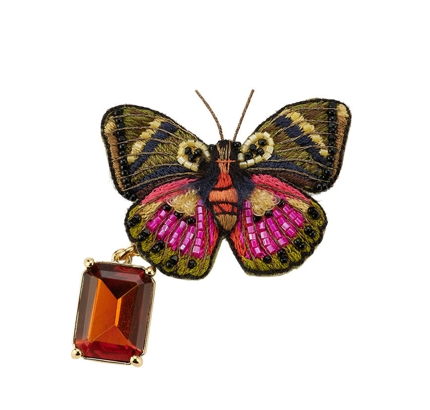 Butterfly-shaped brooch with gemstone on a white background