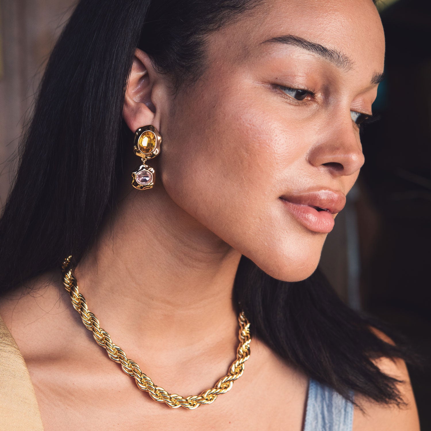 Close-up of a woman wearing gold jewelry including earrings and a necklace.