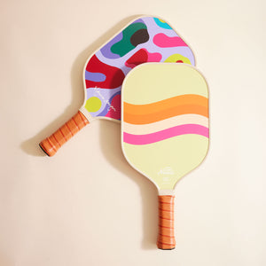 Set of Multi-Colored Pickleball Paddles with Leather Handles Styled on Cream Background