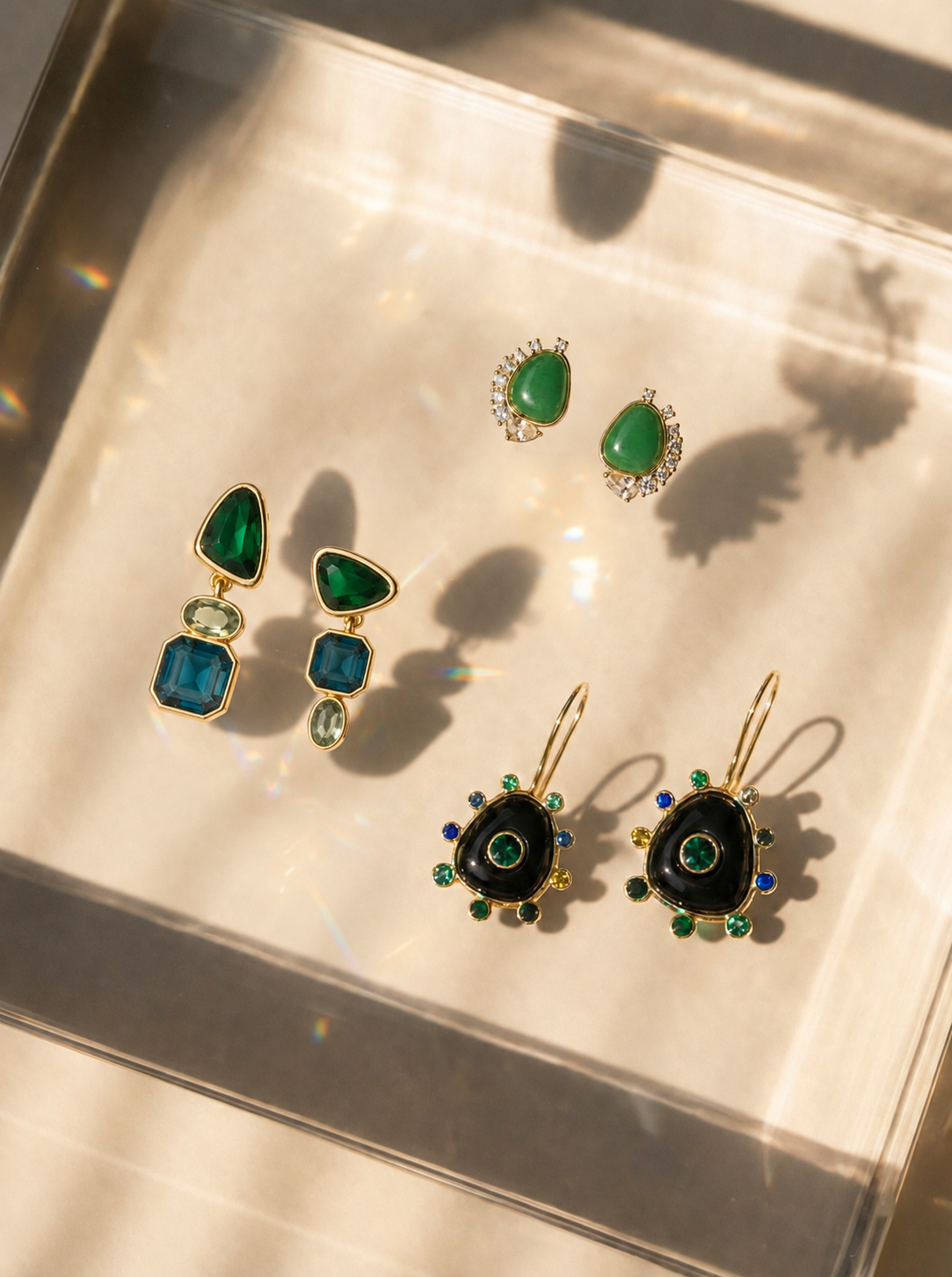 Three sets of statement earrings on a glass reflective background