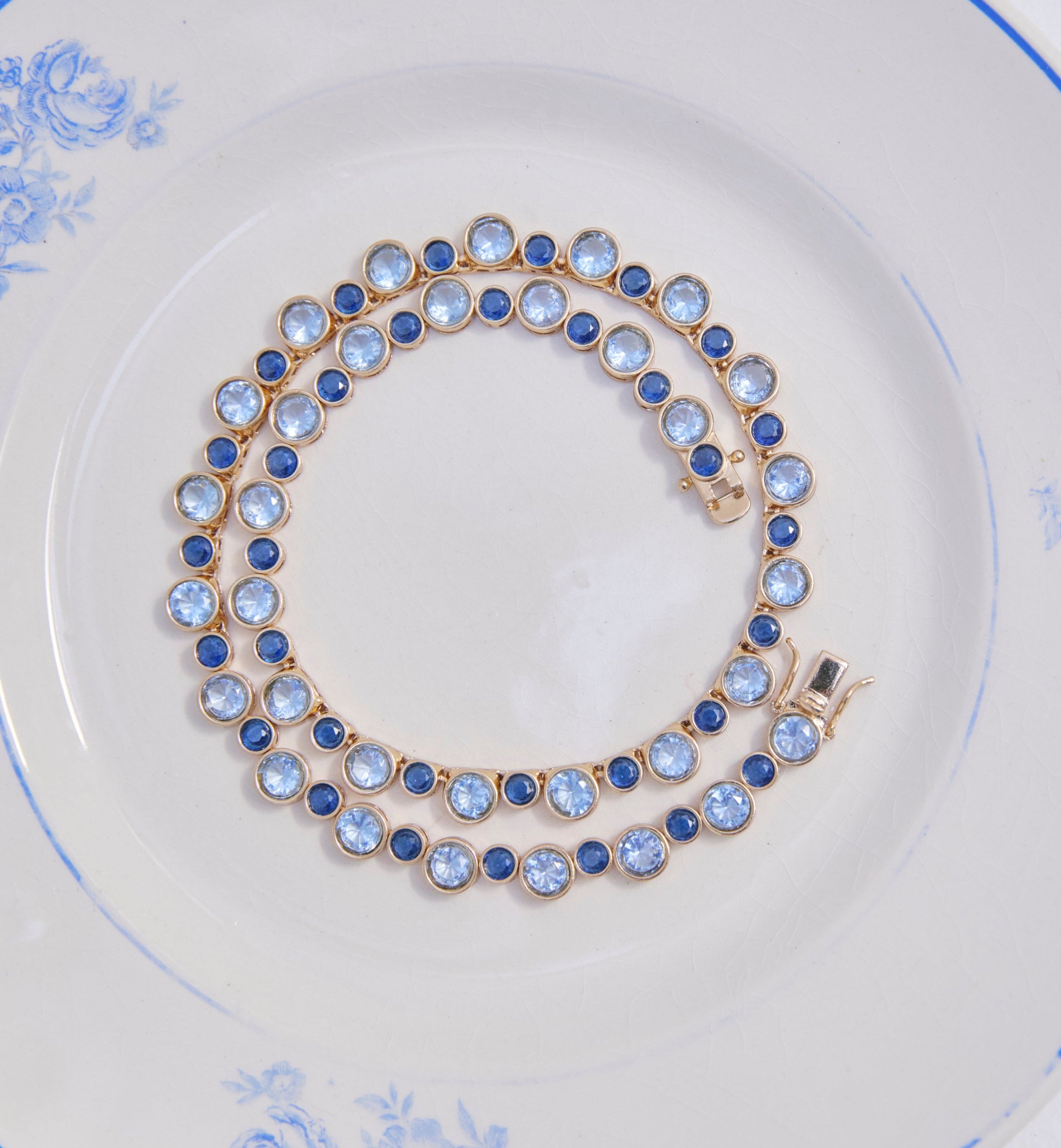 Blue multi tennis necklace on a blue and white plate