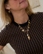 A close-up of a woman wearing gold heart-shaped dangle earrings and a gold pendant necklace.
