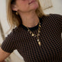 A close-up of a woman wearing gold heart-shaped dangle earrings and a gold pendant necklace.