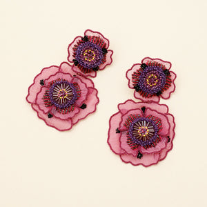 Magenta, Red, Purple, and Yellow Embroidered and Beaded Flower Drop Earrings on Tan Background