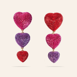 Metallic Red, Purple, and Pink Embroidered Heart Triple Drop Earrings on Cream Background