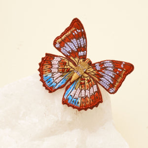 Red and Pruple Multi Beaded and Embroidered Butterfly Brooch Staged on Marble with Cream Background