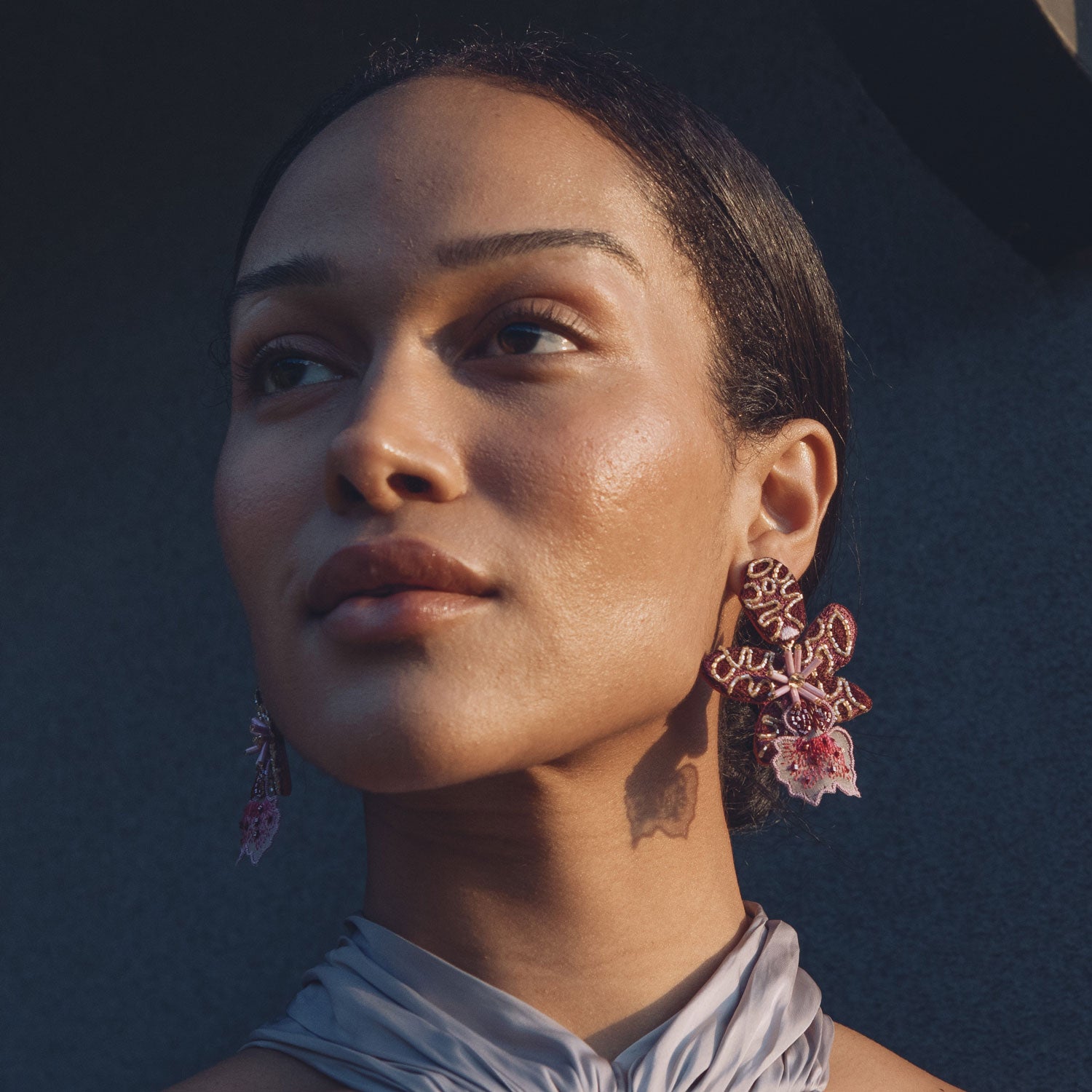 Woman wearing floral earrings against a dark background