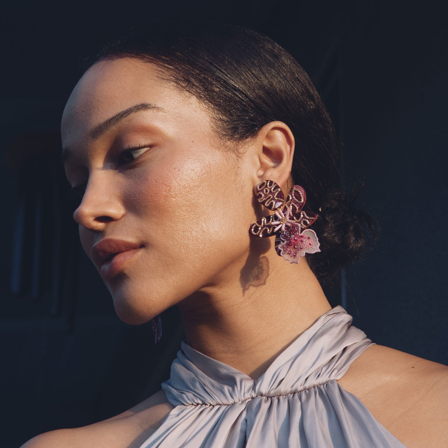 Woman wearing floral earrings with a dark background
