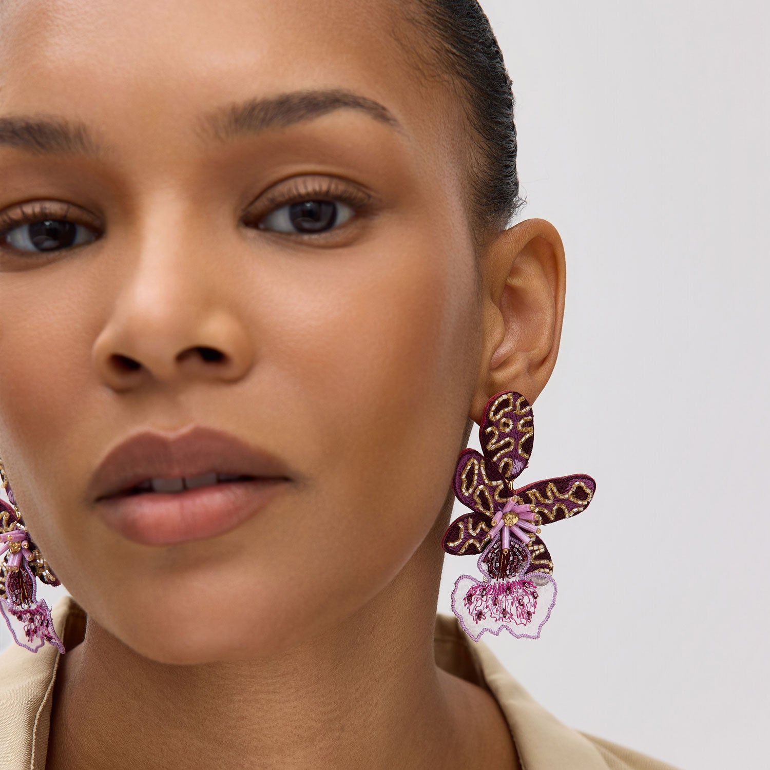 Close-up of a woman wearing flower-shaped earrings with a neutral background