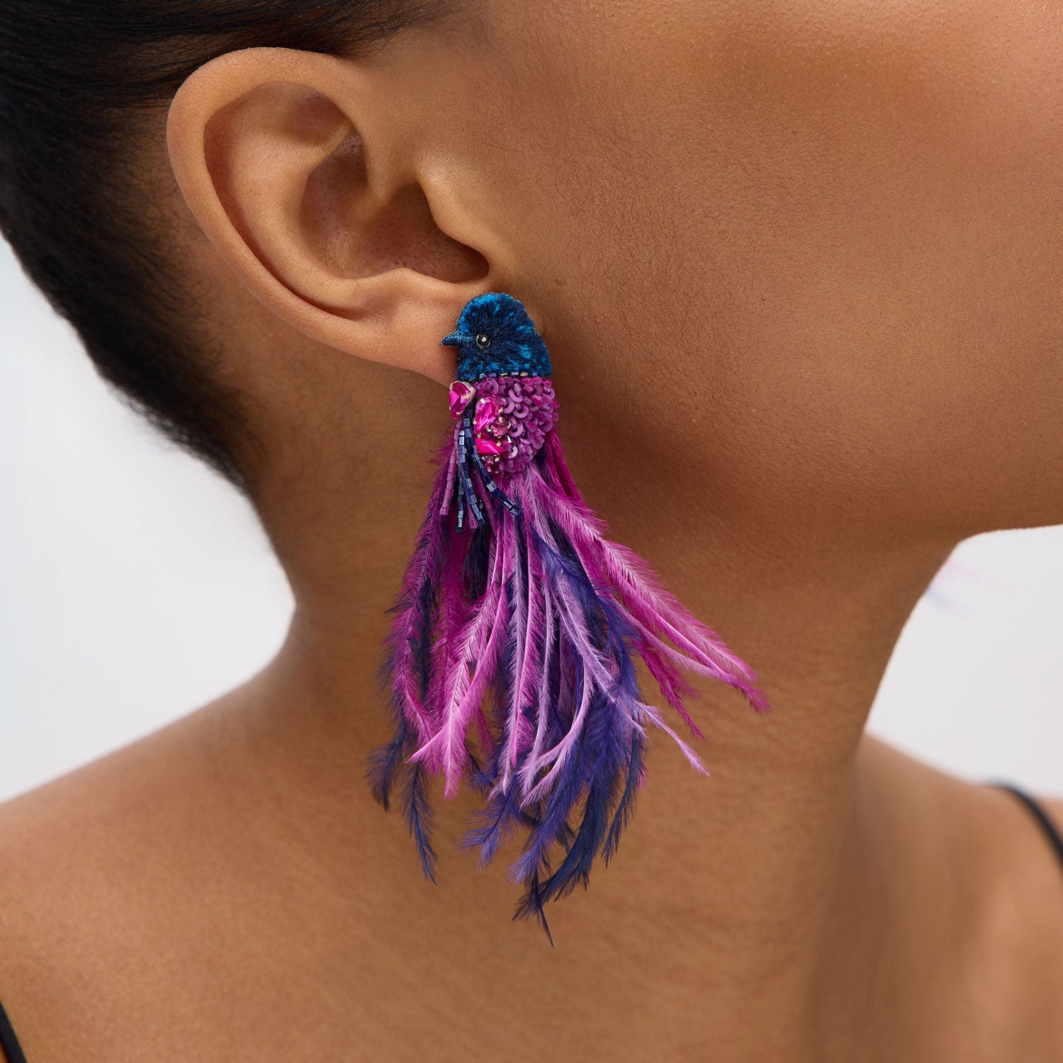 Close-up of a colorful feathered earring worn by a person.