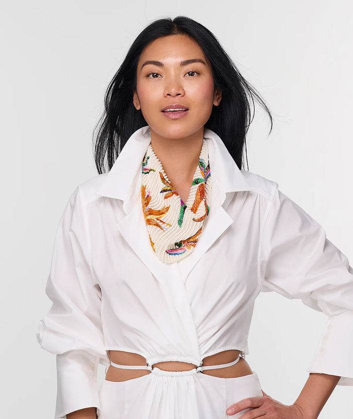 Woman wearing a white shirt and colorful patterned scarf against a white background